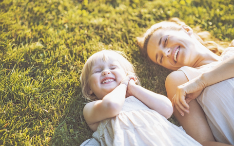 Happy mom and baby laying in the grass together in Waco, TX