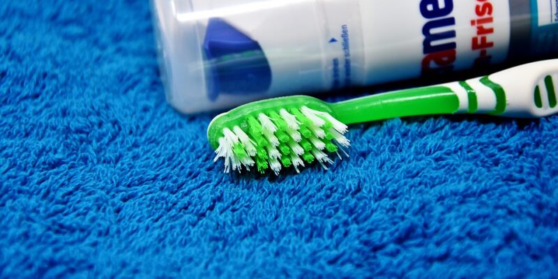 A toothbrush and toothpaste on a blue towel.