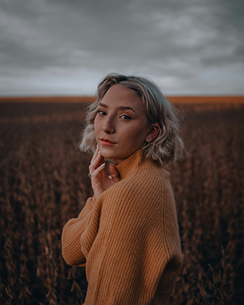 A young female stands in a field holding face from wisdom tooth pain in Waco, TX