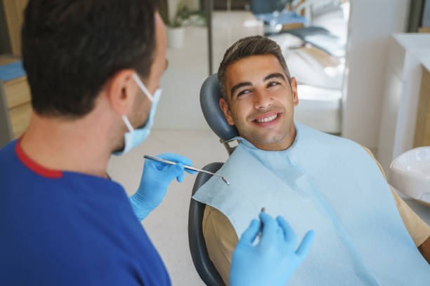 A dentist explaining the Invisalign clear braces for teeth process vs metal braces for teeth, with a smiling patient