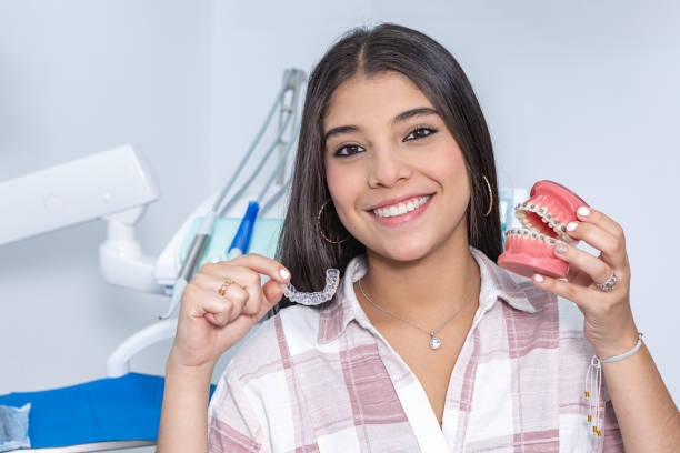 Female patient learning the difference between Invisalign vs braces, smiling with her invisible braces.