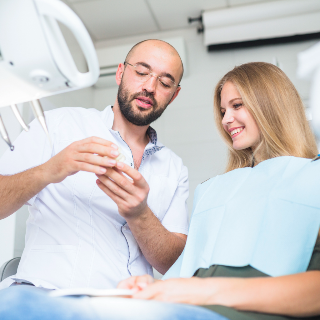 A dentist reviewing X-rays before impacted wisdom teeth removal. The patient is getting a wisdom tooth extraction to get her out of her wisdom tooth pain.