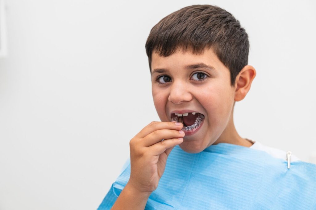 A young boy inserts his teeth braces. He can now enjoy his transformation with Invisalign Teen braces for kids.