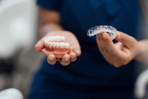 Hands holding dental models, finding a lower cost of Invisalign pricing.