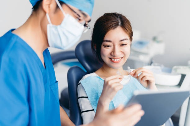One of the best Invisalign dentists consulting with Invisalign near you, showing a female patient how to wear her adult braces.