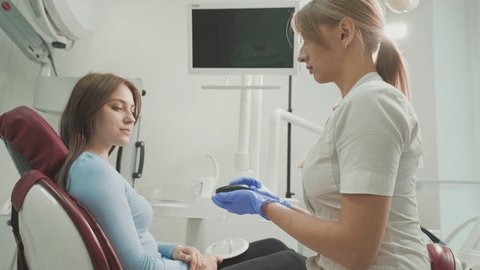 One of the best Invisalign dentists near you, demonstrating how adult braces work to a female patient at an office for Invisalign near you.