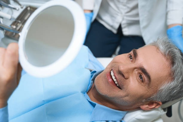 A man happily reviews his new cosmetic dental smile, highlighting our affordable cosmetic dentist near you.