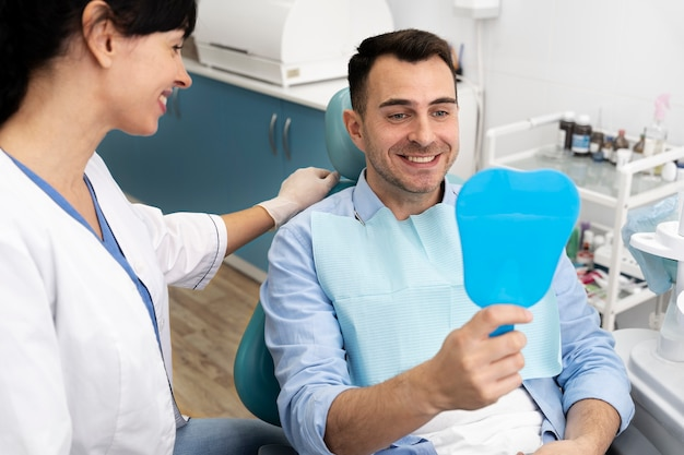 Happy patient looking into a mirror at his new zirconia dental implants, zirconia dental crowns, ceramic tooth crowns, and composite fillings.