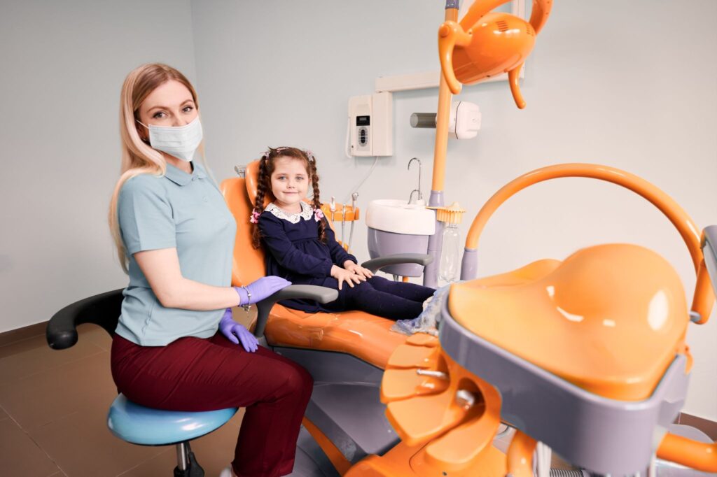 A child in a dental chair giving thumbs-up during a BPA free pediatric composite dental filling.
