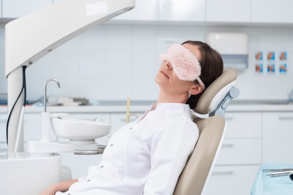 A woman wearing an eye mask relaxes in a dental chair during an obstructive sleep apnea test consultation. She shows signs of sleep apnea and snoring and needs an obstructive sleep apnea test.