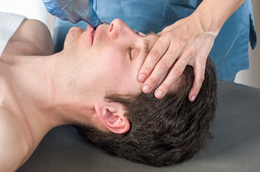 What is TMJ? A therapist performs a jaw and head massage on a man to relieve TMJ symptoms as part of TMD treatment.