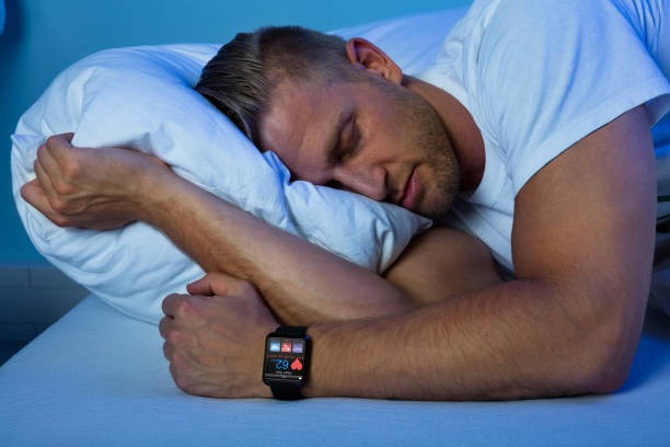 Man sleeping on his side wearing a smartwatch that tracks heart rate and sleep, illustrating sleep monitoring.