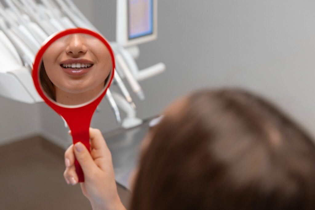 Patient looking at her teeth in a mirror after a bone graft dental procedure.