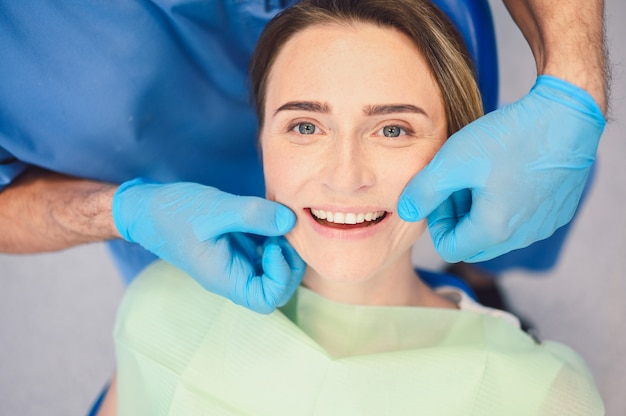 An implant dentist near you, inspecting a patient's smile after an implant dental procedure.