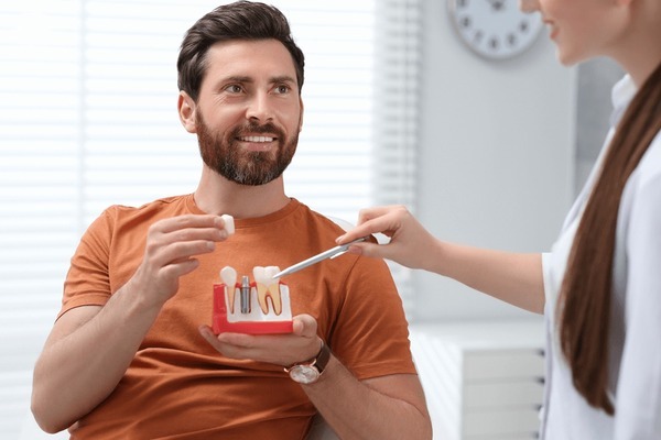 Dentist showing dental implant models to a patient during a dental implant consultation near you.