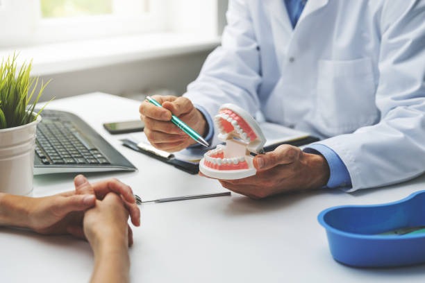 Dentist explaining dental implant options to a patient using a dental model during a dental implant consultation near you.