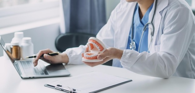 A dentist with a computer showing a tooth model during a dental implant consultation near you.